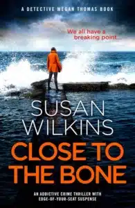 Image of book cover Close To The Bone by Susan Wilkins. A lone female figure standing on a causeway waves crashing around her
